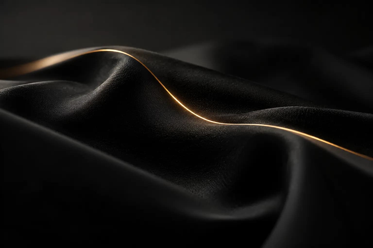 Soft folded black fabric with a thin gold light line